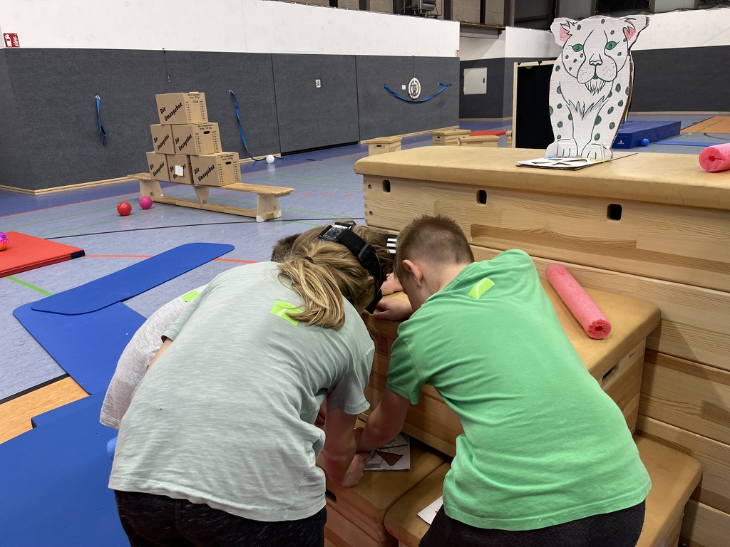 Kinder setzen ein Puzzle in einer Turnhalle zusammen