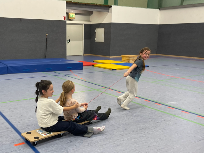 Kinder spielen mit Rollbrett in einer Turnhalle