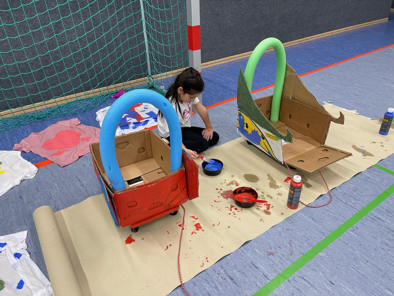 Ein Mädchen bemalt Kartons auf Rollbrettern