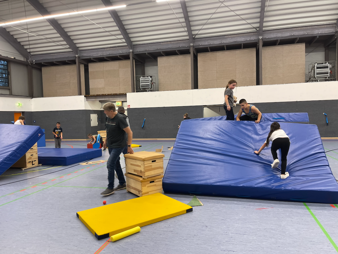 Zusammengestellte Matten in einer Turnhalle werden erklettert.
