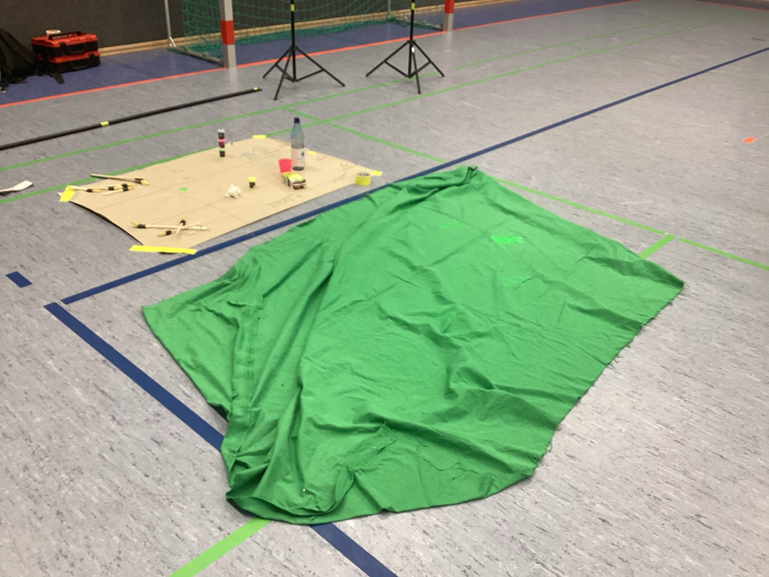 Ein großes Tuch für Greenscreen wurde mit einem Handabdruck in Schwarzlichtfarbe versehen.