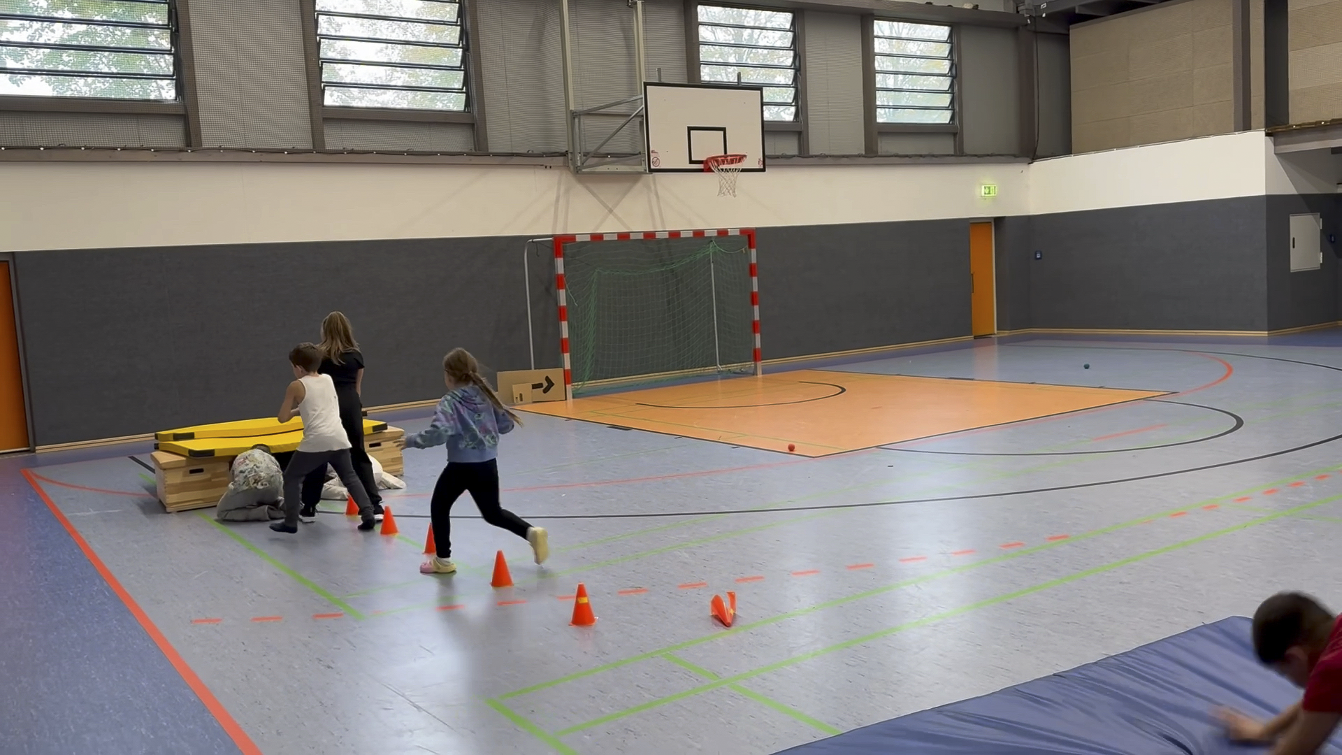 Kinder vor einem Tunnel aus Sportgeräten in einer Turnhalle