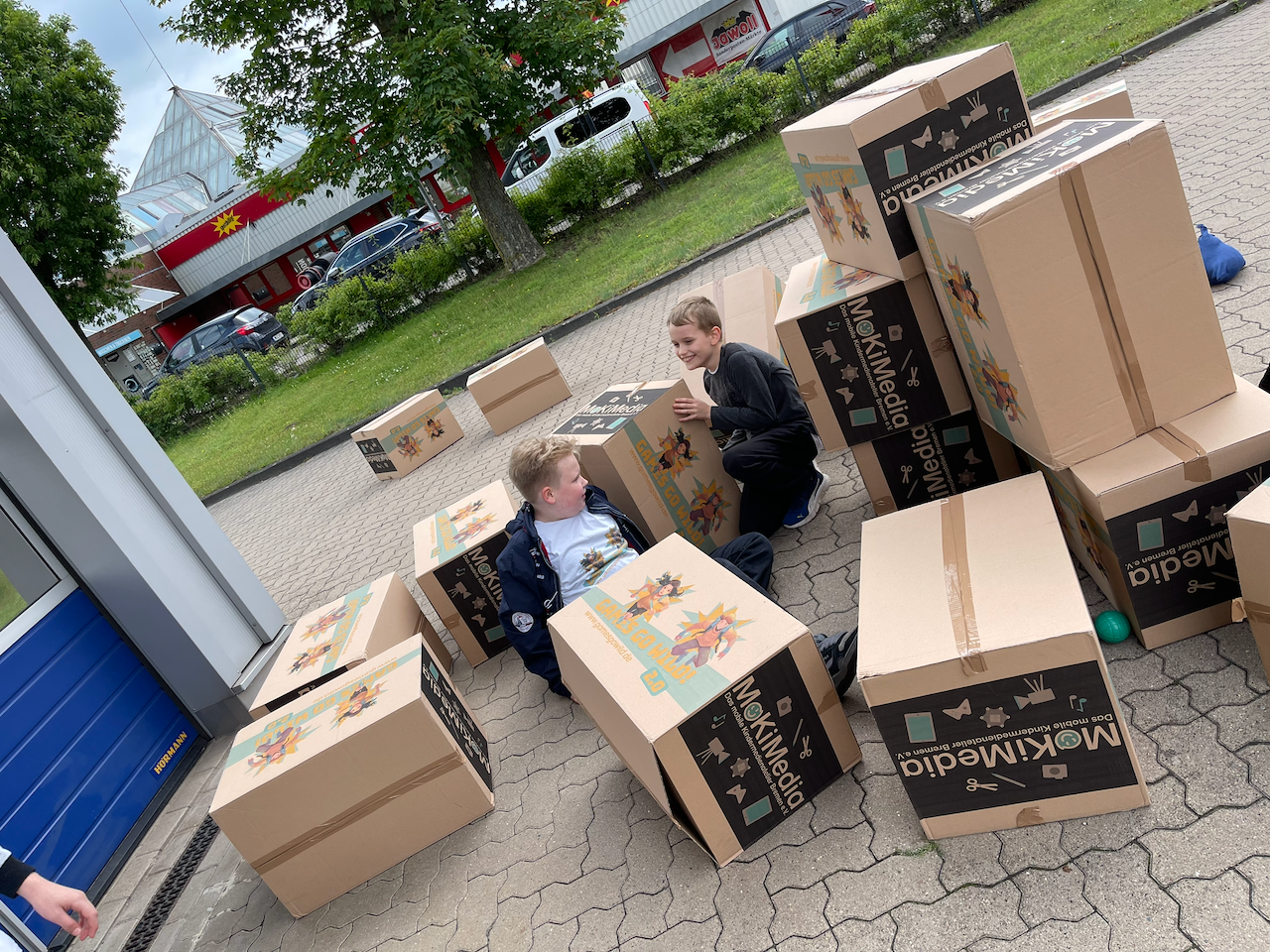 2 Jungen sitzen zwischen vielen Kartons