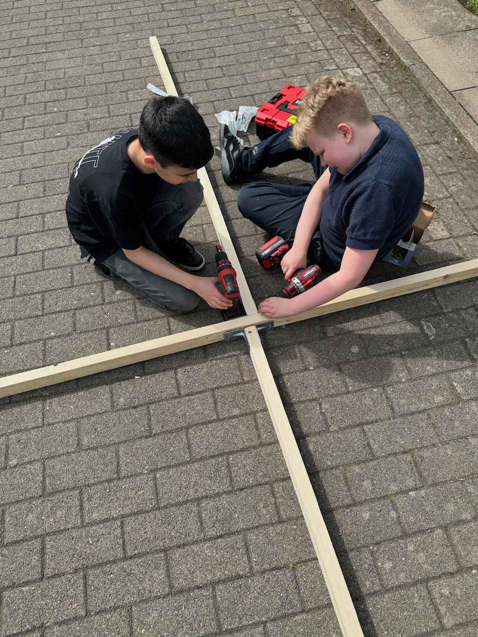 Zwei Jungen schrauben ein Gestellt zusammen.
