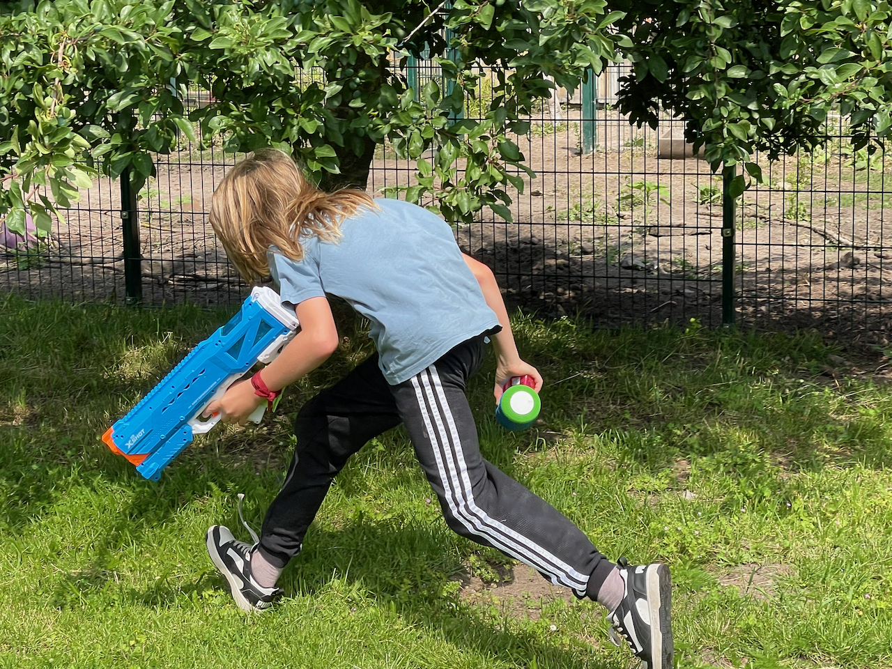 Junge mit Wasserpistole läuft geduckt.