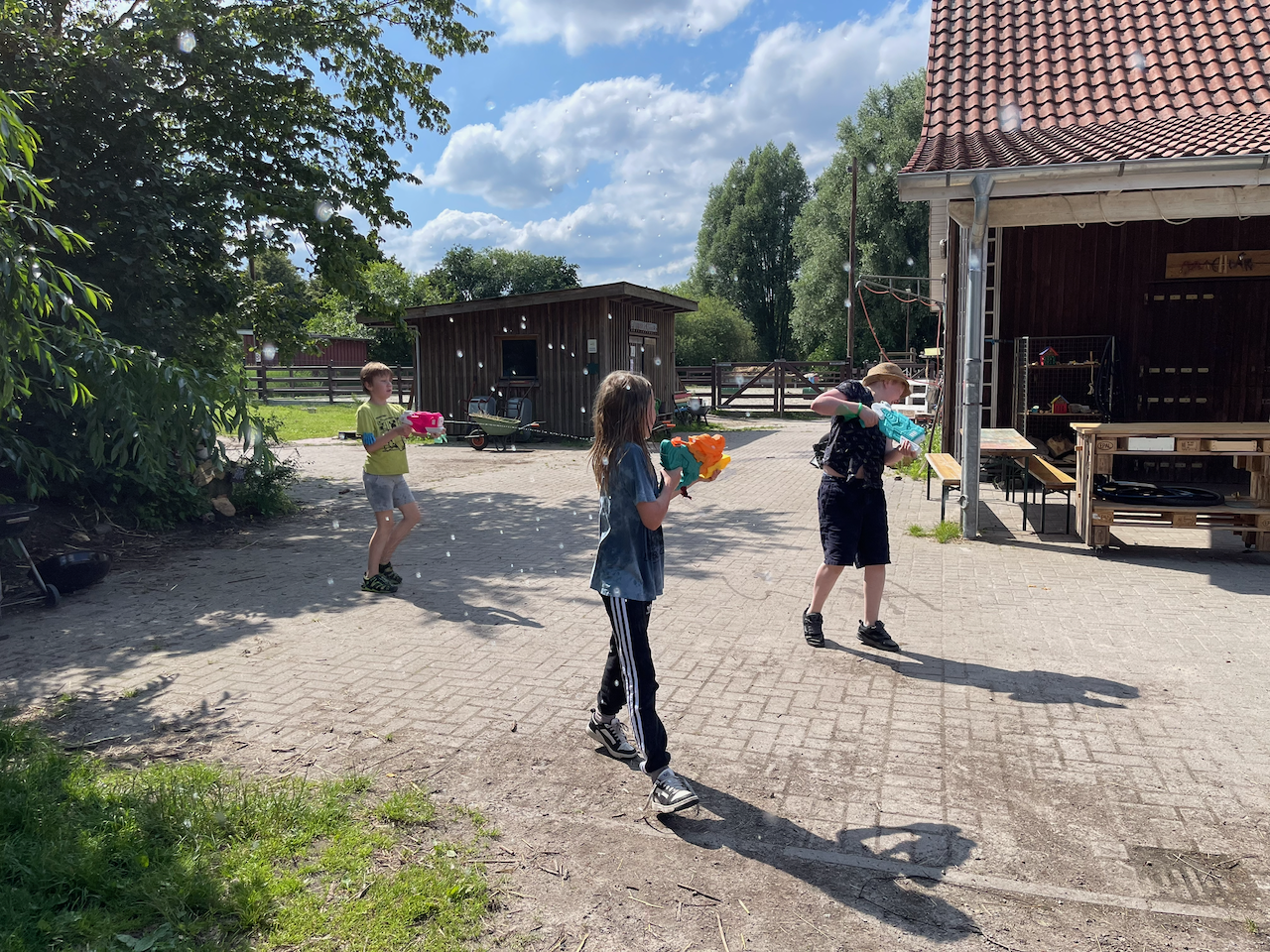 3 Jungen schießn sich mit Wasserpistolen ab.