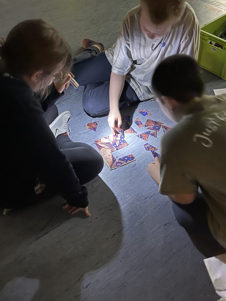 Zwei Kinder und Mutter lösen Puzzle auf Hallenfußboden
