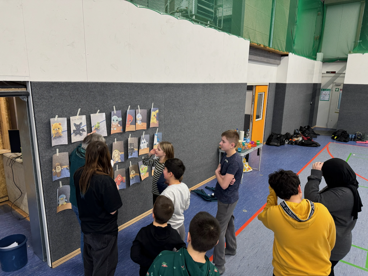 Kinder suchen Namen für Brainrotts (Fotos von Kuscheltieren ausgedruckt an Wand)