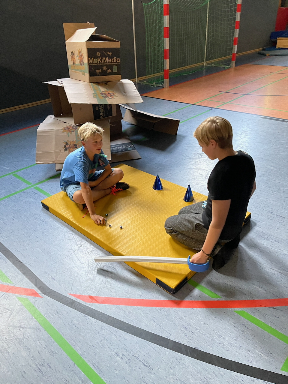 Zwei Jungen würfeln gegeneinander in einer Turnhalle