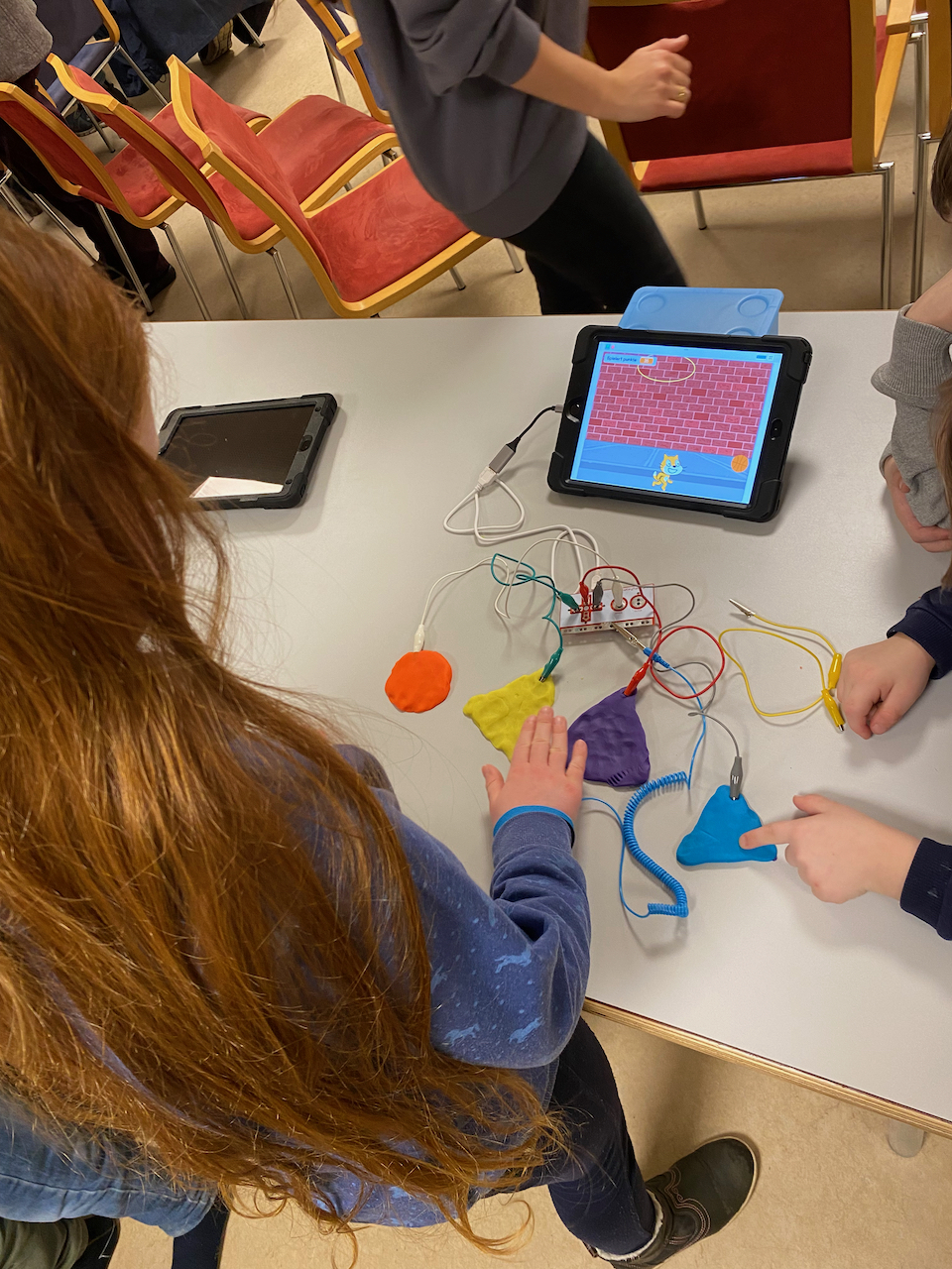 Ein Mädchen spielt am Tablet ein Spiel in Scratch