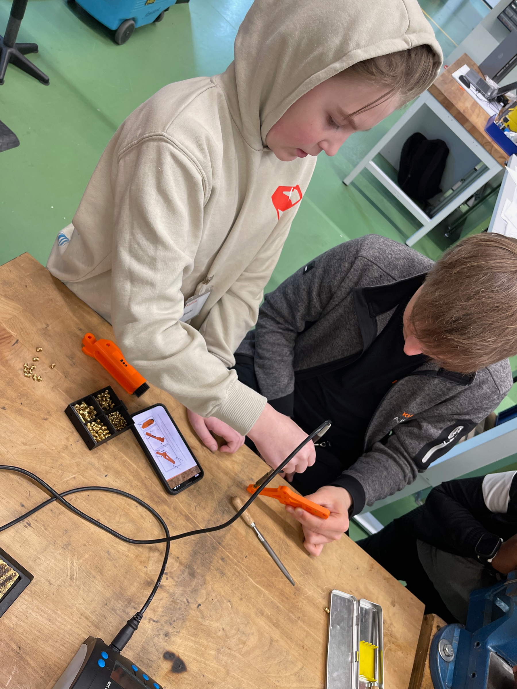 Bei Kuka: Junge versenkt Schrauben mit einem Lötkolben in ein 3D-gedrucktes Bauteil