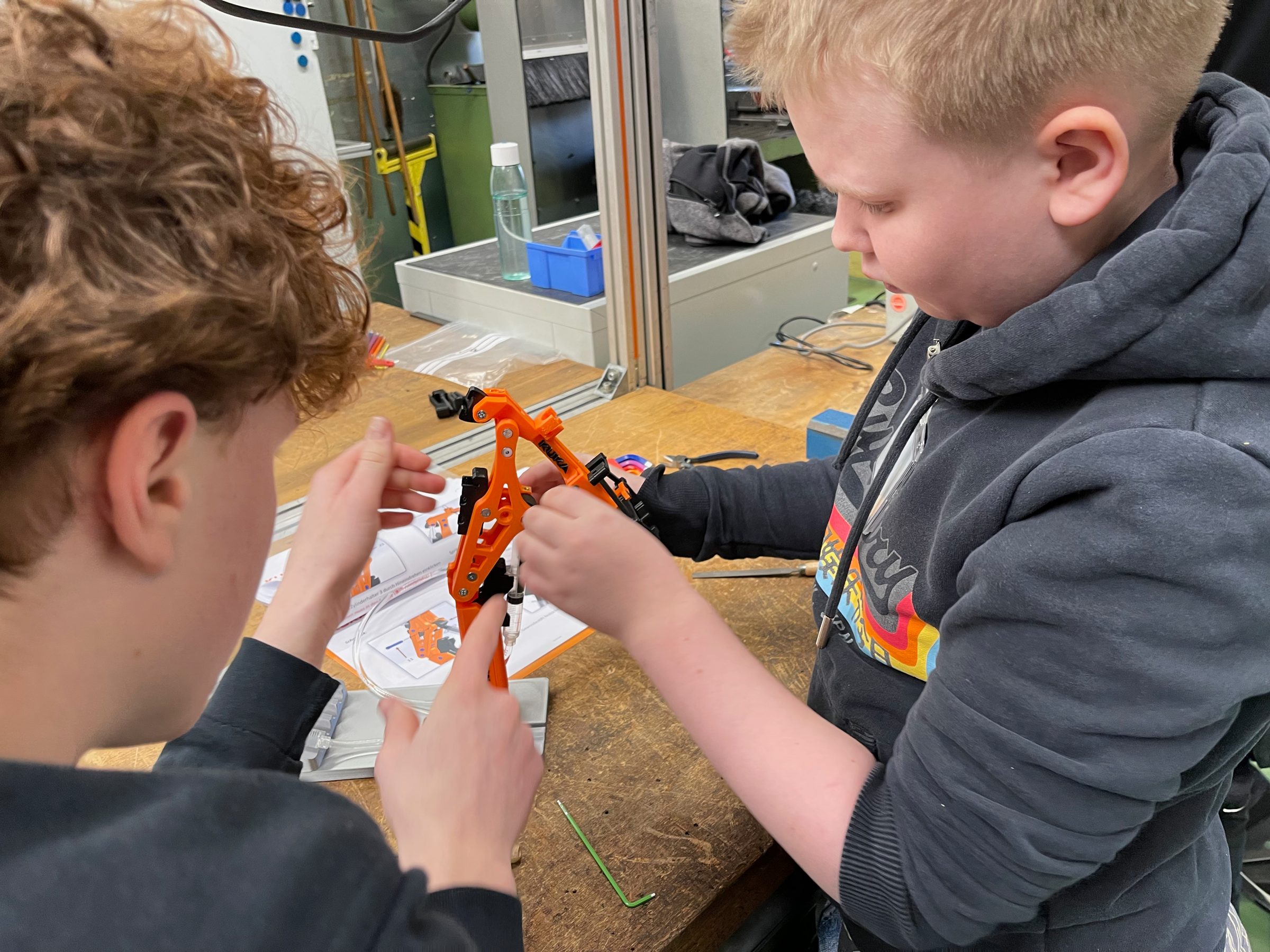 Bei Kuka: Junge baut mit Unterstützung einen Roboterarm zusammen