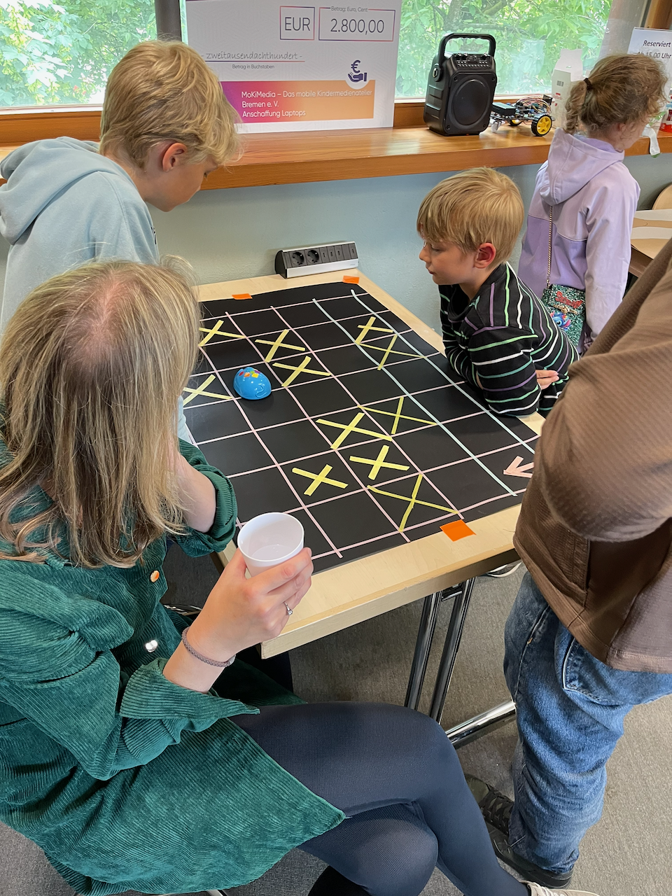 Zwei Jungs und eine Frau an einer Platte mit robomouse.